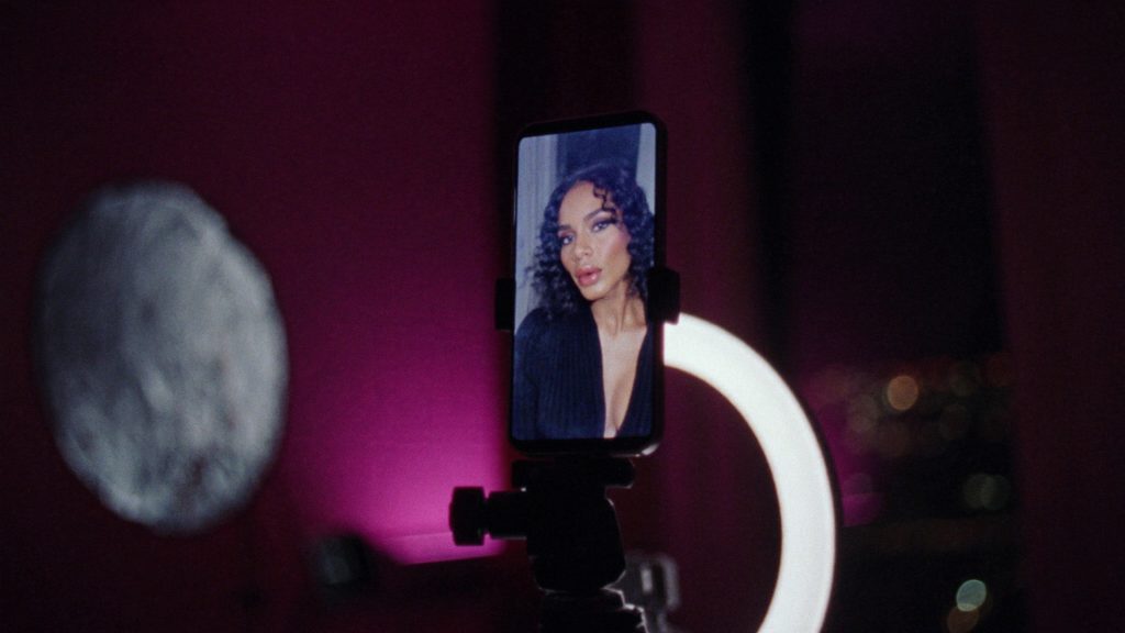 A creator filming herself on a phone with a ring light at night